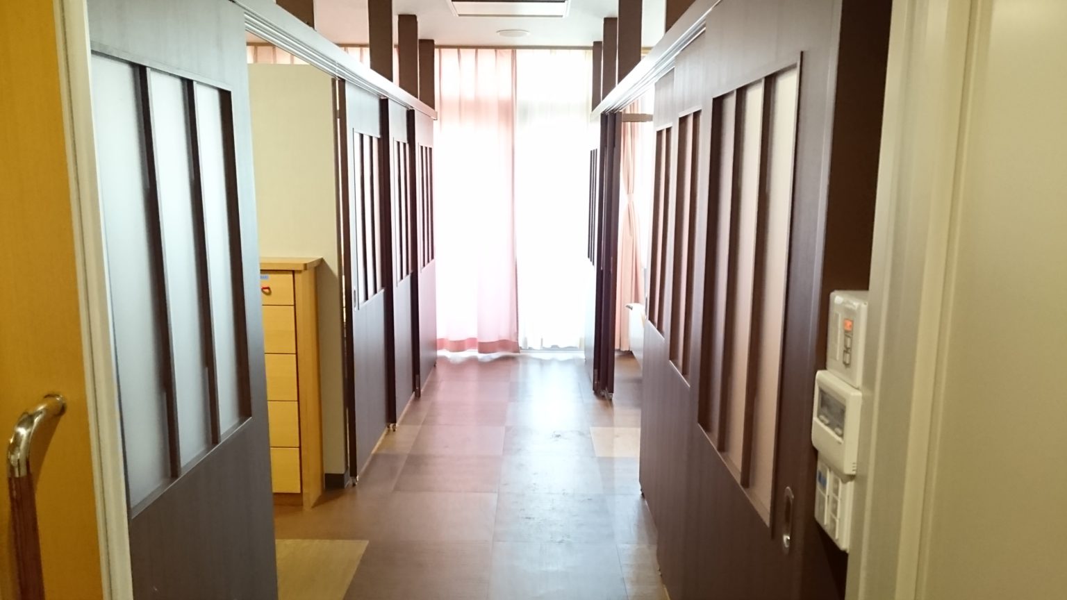 廊下の両側に複数の居室ドアが並ぶ介護施設の共用廊下